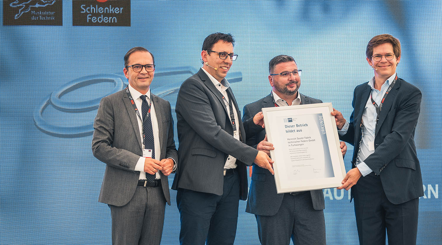 Sauter Federn Slider-Motiv: 4 Männer auf der Präsentationsbühne, Überreichnung der IHK-Urkunde