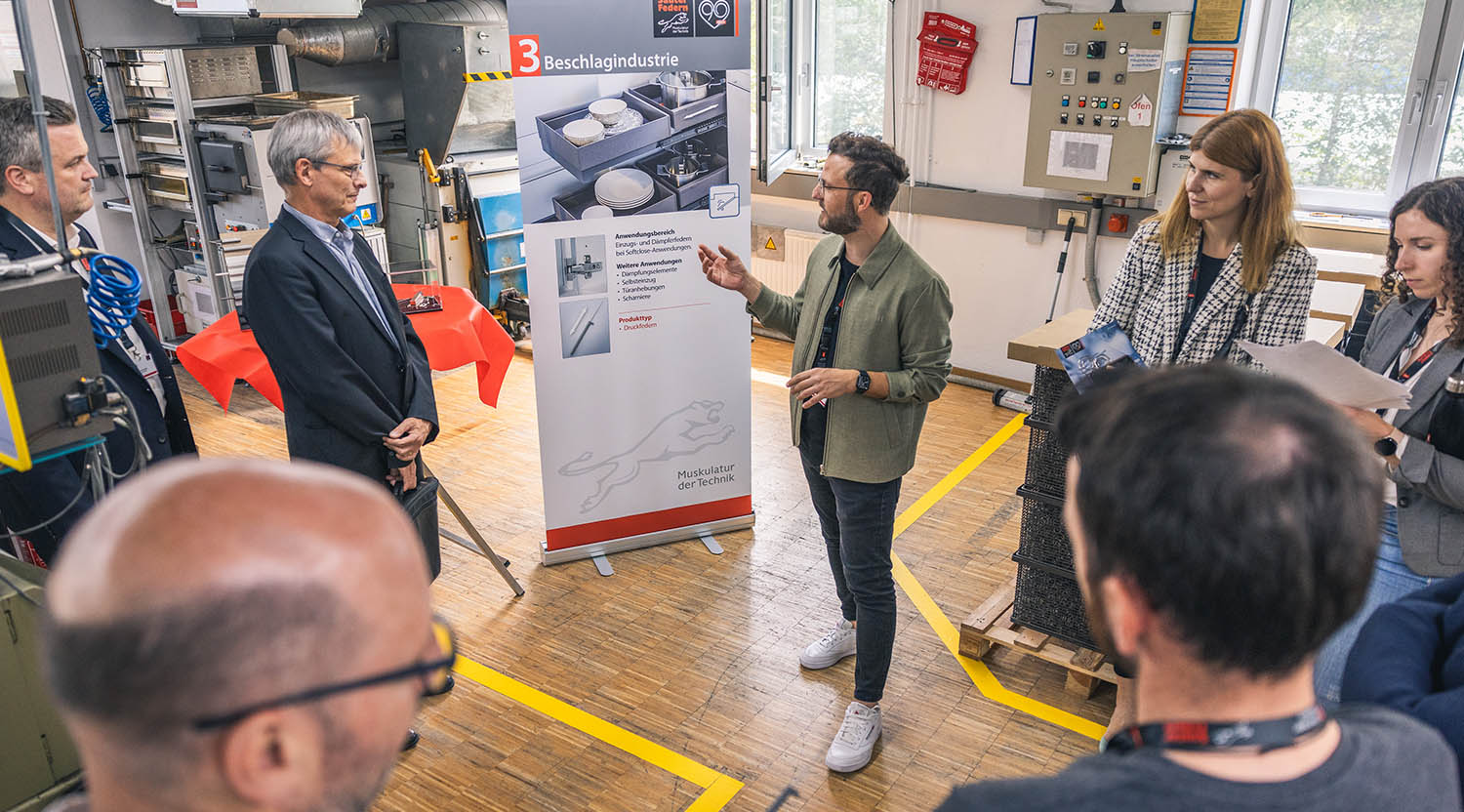 Sauter Federn: Erklärungssituation vor einem Rollup-Plakat beim Tag der offenen Tür zum neunzigjährigen Firmenjubiläum