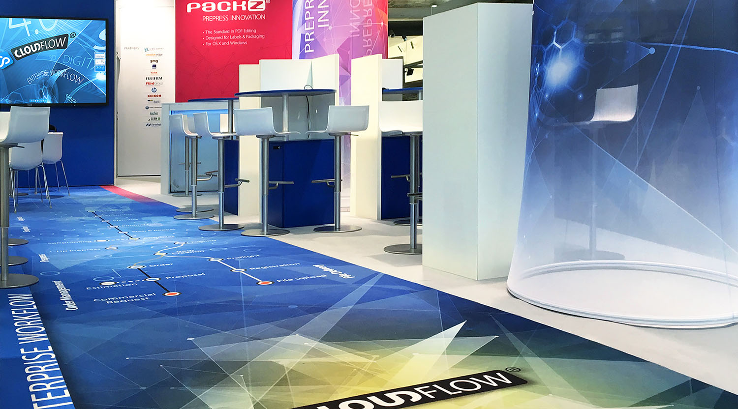 Hybrid Software: Messestand mit leuchtenden Türmen aus gespanntem Gewebe sowie einem mit dem Arbeitsablauf von "CLOUDFLOW" bedruckten Teppich.